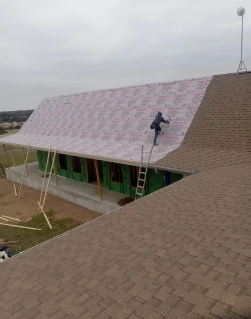 Worker preparing underlayment for a metal roof installation in Milan